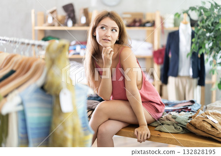 Sexy woman playfully posing on table in fashion store 132828195