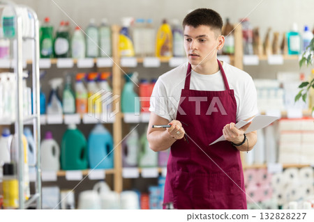 Male seller makes notes on paper - keeps track of the receipt and expenditure of goods in supermarket Male seller makes notes on paper - keeps track of the receipt and expenditure of goods in supermarket 132828227