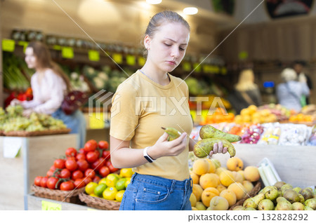 Young woman choosing a pear on the counter background Young woman choosing a pear on the counter background 132828292