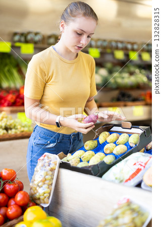 Teenage girl chooses indian fig in store Teenage girl chooses indian fig in store 132828315