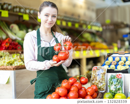 Female seller laying out tomatoes on the counter 132828339