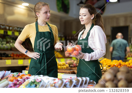 Two female sellers putting persimmons in store Two female sellers putting persimmons in store 132828359