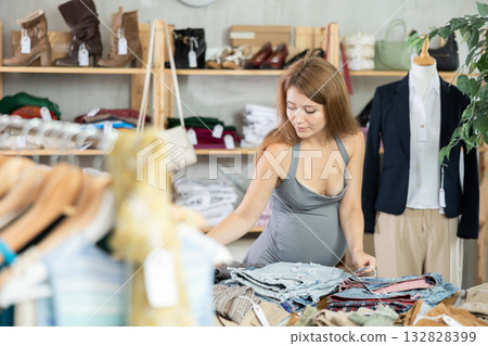Pregnant woman shopping in clothing department, buying denim pantalones 132828399