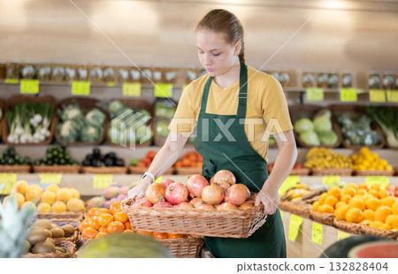Female seller holding a basket of ripe pomegranates 132828404