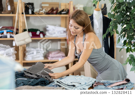 Woman shopping in clothing department, buying denim pantalones 132828411