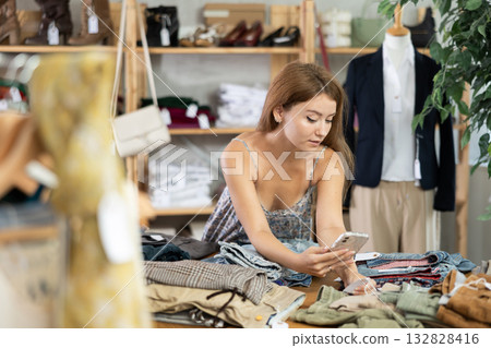 Young woman checking the quality of jeans using a steamer QR code on label 132828416