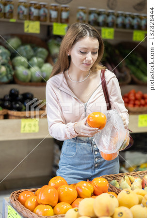 Young woman chooses persimmons in store 132828444