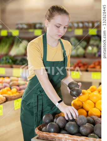 Portrait of girl working in grocery shop as job experience, selling avocado 132828445