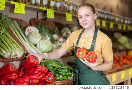 Woman employees in uniform holding fresh bell pepper in grocery shop Woman employees in uniform holding fresh bell pepper in grocery shop 132828446