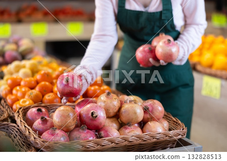 Hands of a woman seller puts ripe pomegranate in store 132828513