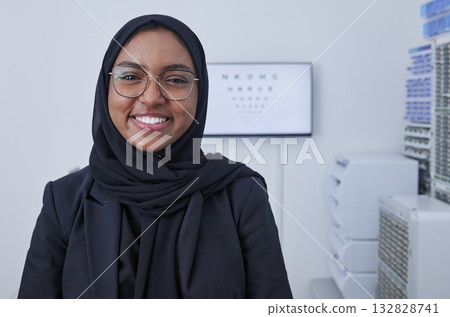 Hijab, happy muslim woman and optometrist portrait in a doctor office ready for eye test with chart. Healthcare, eyes wellness and proud clinic worker with a smile with company vision and success 132828741