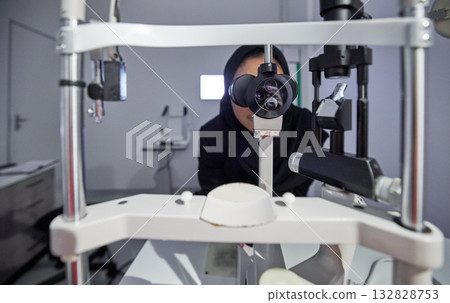 Optometry, healthcare and optometrist doing eye test in the clinic for eyecare and vision wellness. Medical, ophthalmology and muslim female optician doing optical exam with equipment at optic store. 132828753
