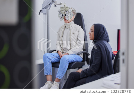 Vision, eye exam and senior woman with optometrist in clinic for testing, eyesight and optical assessment. Optometry, healthcare and Muslim optician with patient, phoropter and medical tool for eyes Vision, eye exam and senior woman with optometrist in clinic for testing, eyesight and optical assessment. Optometry, healthcare and Muslim optician with patient, phoropter and medical tool for eyes 132828778
