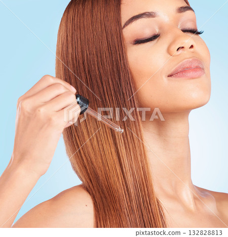 Eyes closed, beauty hair care and woman with serum in studio isolated on a blue background. Hairstyle cosmetics, face and young female model apply hyaluronic acid or essential oil for salon treatment Eyes closed, beauty hair care and woman with serum in studio isolated on a blue background. Hairstyle cosmetics, face and young female model apply hyaluronic acid or essential oil for salon treatment 132828813