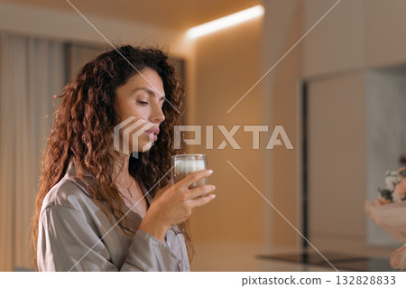 Curly haired woman in pajamas having coffee at Curly haired woman in pajamas having coffee at 132828833