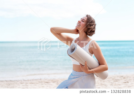 Sporty slim woman in activewear holding rolled 132828838