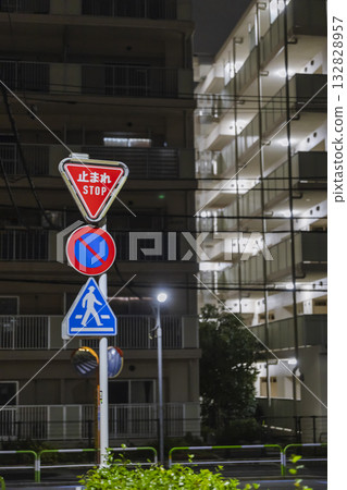 Stop signs with LED lights and a housing complex at night 132828957