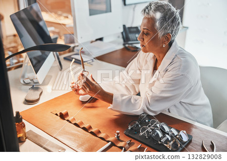 Senior optometrist woman, glasses and design for focus, vision or frame planning at desk in clinic. Elderly optician, spectacle designer and eye care in workplace for fashion, small business and goal 132829008