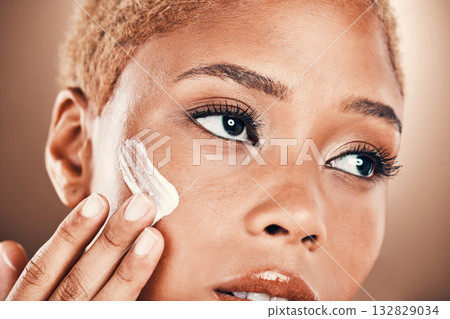 Moisturizer, cream and black woman with beauty skincare and face lotion in studio. Brown background, isolated and collagen cosmetic dermatology of a model with makeup and skin glow for facial Moisturizer, cream and black woman with beauty skincare and face lotion in studio. Brown background, isolated and collagen cosmetic dermatology of a model with makeup and skin glow for facial 132829034