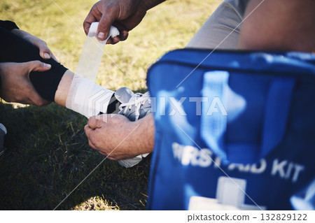 First aid, hands and man medic with ankle sports injury at field for running, training or marathon practice. Medical, closeup and emergency service for runner person with injured foot during workout 132829122