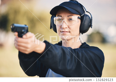 Woman, gun and learning to shoot weapon at shooting range outdoor for security, training and target. Person with safety headphones and glasses for sport, competition or safety with gear in hands Woman, gun and learning to shoot weapon at shooting range outdoor for security, training and target. Person with safety headphones and glasses for sport, competition or safety with gear in hands 132829123