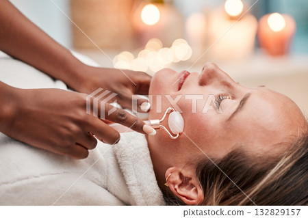 Facial roller, spa and woman getting a massage for self care, wellness and health at beauty salon. Skincare, relax and calm young female doing a luxury natural face or skin treatment for dermatology. Facial roller, spa and woman getting a massage for self care, wellness and health at beauty salon. Skincare, relax and calm young female doing a luxury natural face or skin treatment for dermatology. 132829157