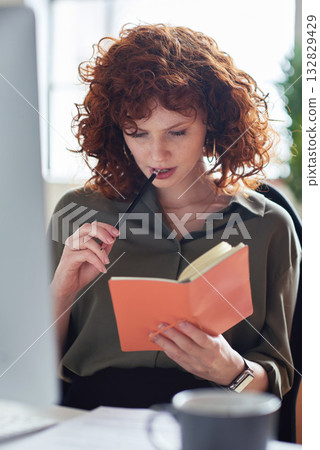 Thinking, planning or graphic designer woman reading notebook for creative research, web strategy or branding. Startup office or serious girl employee at desk working on SEO report, notes or journal 132829429
