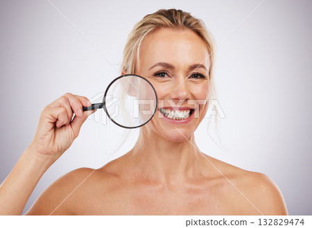 Portrait, beauty and magnifying glass with a mature woman in studio on a gray background to examine her skin. Face, wrinkle and antiaging with an attractive female confident in her natural skincare Portrait, beauty and magnifying glass with a mature woman in studio on a gray background to examine her skin. Face, wrinkle and antiaging with an attractive female confident in her natural skincare 132829474
