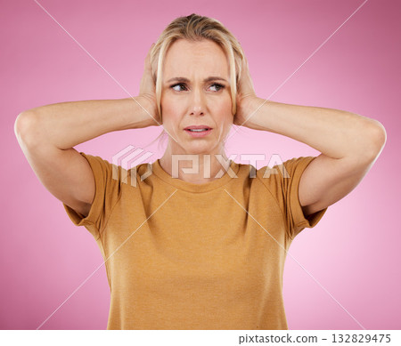 Loud, studio and woman closing her ears in a studio for noise distraction, sound or complaint. Upset, mad and annoyed female model with a hands on her head for cover isolated by a pink background. 132829475