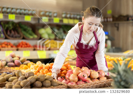 Female seller holding a basket of ripe pomegranates 132829680