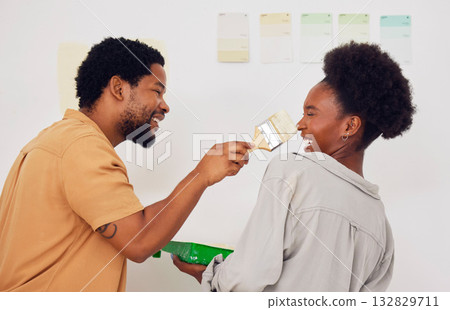 Painting, funny or happy black couple in DIY, home renovation or house remodel together with a paintbrush. Playing, smile or crazy African man laughing with woman working or decorating with team work 132829711