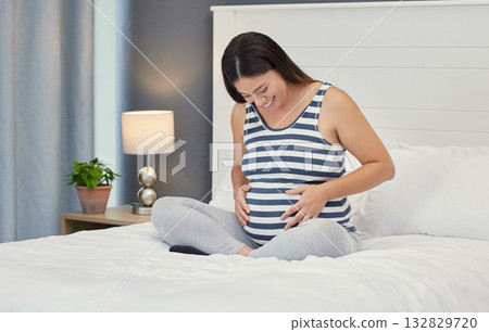Pregnant stomach, woman and home bedroom while happy about bonding and growth. Mother to be person with hands on abdomen for healthy pregnancy development, body wellness and care or love on her bed Pregnant stomach, woman and home bedroom while happy about bonding and growth. Mother to be person with hands on abdomen for healthy pregnancy development, body wellness and care or love on her bed 132829720