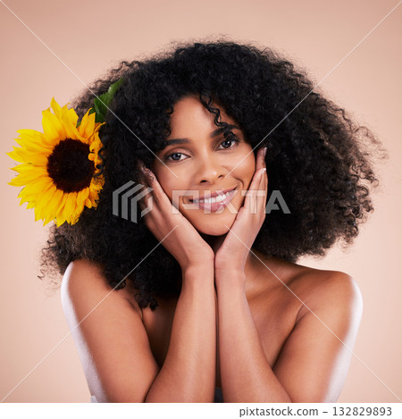 Black woman, studio portrait and sunflower with beauty, smile and cosmetic wellness by beige background. African gen z model, flower and spring aesthetic with hands, happy and natural makeup on face Black woman, studio portrait and sunflower with beauty, smile and cosmetic wellness by beige background. African gen z model, flower and spring aesthetic with hands, happy and natural makeup on face 132829893