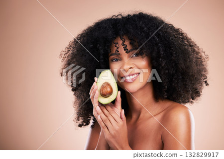Black woman, studio portrait and avocado for beauty, cosmetic skincare or health for wellness, smile or self care. Happy gen z model, african or fruit for natural aesthetic, healthy nutrition or diet 132829917