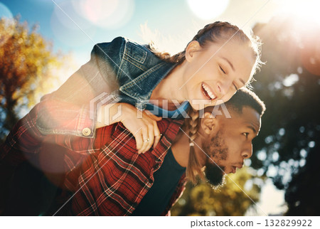 Interracial couple piggyback in park, summer and outdoor date together in sunshine, happiness and nature. Happy man carrying woman in garden for young love, care and freedom to relax and smile 132829922
