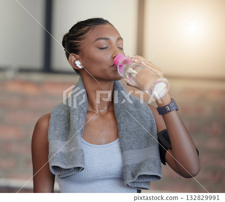 Woman, fitness and drinking water for hydration, workout break or thirsty from intense training at gym. Tired female with bottle or refreshment for thirst, recovery and sweat towel in cardio exercise 132829991