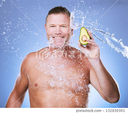 Portrait, water splash with man and avocado for skincare, eco friendly and vegan beauty cosmetics on blue background. Hygiene, hydration and mature male smile, detox facial and fruit with face care 132830301