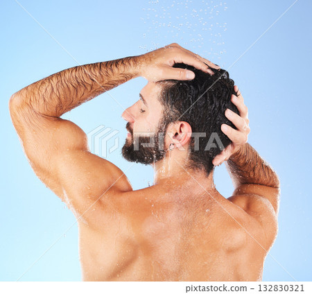 Hair care, shower wash and man model in water for cleaning, skincare and hygiene wellness. Isolated, blue background and studio with a young person in bathroom for dermatology and self care routine Hair care, shower wash and man model in water for cleaning, skincare and hygiene wellness. Isolated, blue background and studio with a young person in bathroom for dermatology and self care routine 132830321
