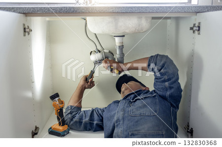 Plumber, man and handyman with plumbing, home renovation and manual labour with tools. Construction, DIY skills and professional, fixing pipe in industry and male with trade, repairs and maintenance 132830368