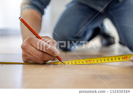Handyman, floor and hands to measure with pencil, tape and diy for home improvement, maintenance and building. Builder, construction worker and flooring with writing, planning and vision in workplace 132830384
