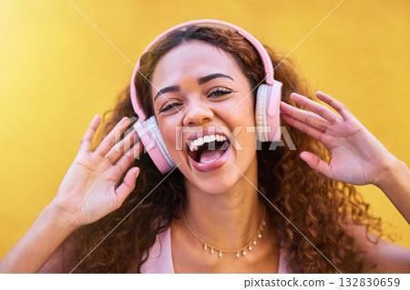 Music, portrait and laughter with a black woman listening to the radio outdoor on a yellow wall background. Headphones, energy and face with an attractive young female streaming audio sound for fun Music, portrait and laughter with a black woman listening to the radio outdoor on a yellow wall background. Headphones, energy and face with an attractive young female streaming audio sound for fun 132830659