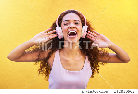 Music, portrait and laughter with a black woman listening to the radio outdoor on a yellow wall background. Headphones, energy and face with an attractive young female streaming audio sound for fun Music, portrait and laughter with a black woman listening to the radio outdoor on a yellow wall background. Headphones, energy and face with an attractive young female streaming audio sound for fun 132830662