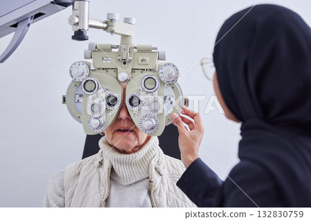 Eye exam, vision and senior woman with optometrist in clinic for testing eyes, check eyesight and optical care. Optometry, healthcare and Muslim optician with patient, phoropter and medical tools 132830759
