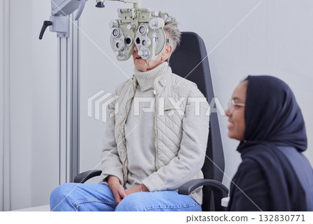 Optometry, ophthalmology and Islamic optometrist in Dubai consulting a patient for an eye test using a Phoropter for vision. Eyesight, woman and Muslim person with hijab doing optical examination 132830771