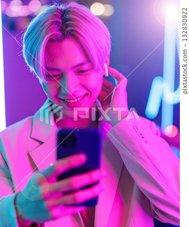 A young man holding a smartphone and wearing wireless earphones A young man holding a smartphone and wearing wireless earphones 132830922