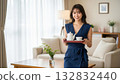 A smiling woman carrying a tea set in the living room 132832440