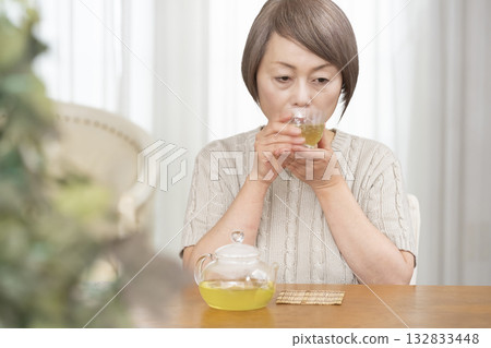 夏天，一位老婦人在客廳喝冰茶。 132833448