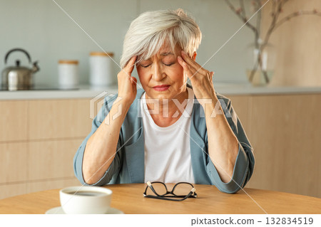 Headache pain. Unhappy middle aged senior woman suffering from headache sick rubbing temples at home. Mature old senior grandmother touching temples experiencing stress Woman feeling pain hurt in head 132834519
