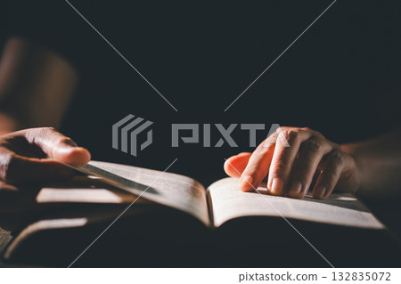 Hands clasped in prayer over the holy Bible, the faithful Christian worships God in church, holding onto hope and belief, guided by religion and a deep commitment to their religious faith. 132835072