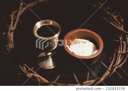 Communion bread and wine with the Holy Bible and crown of thorns, symbolizing the sacrifice of Jesus Christ, the passion, salvation and Christian faith in the Eucharist and Lord Supper. 132835156
